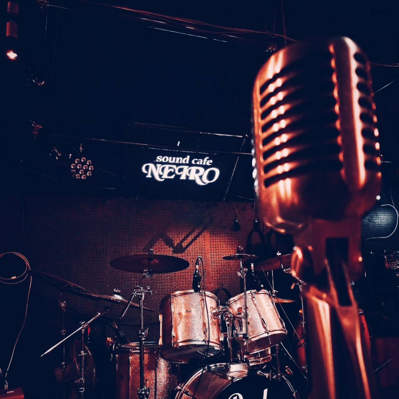 ステージのマイクとドラムセット、sound cafe NEIROのロゴ看板